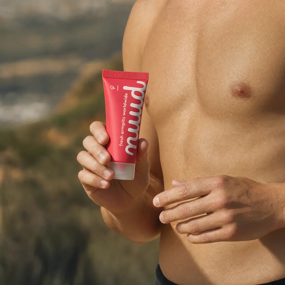 A man holding a tube of nuud, outdoors on a hillside